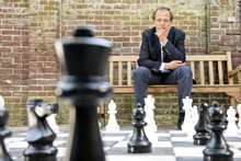 Thinking Man Sitting At A Life Sized Outdoor Chess Board