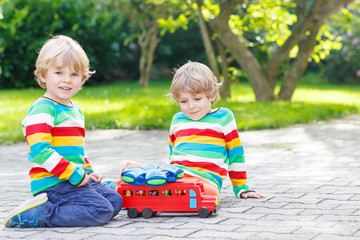 Wall Mural - Two siblings, kid boys playing with red school bus