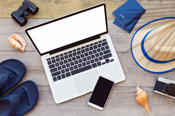 Laptop computer and smart phone with male summer holiday accessories on wooden board