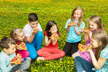  Happy children eating pizza outdoors