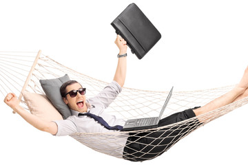 Wall Mural - Young businessman lying in a hammock with a laptop in his lap