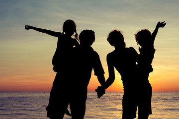 Canvas Print - Silhouette of happy family who playing on the beach at the sunse