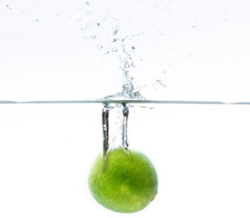 green lemon falling into the water