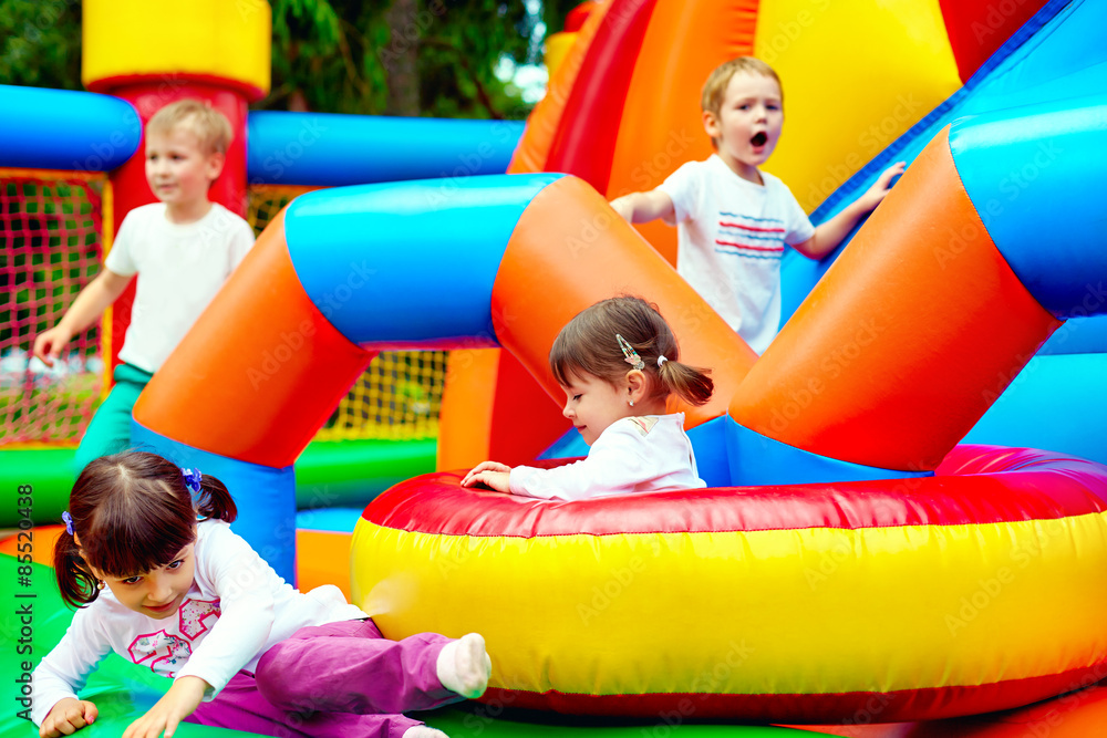 happy kids, having fun on inflatable attraction playground - obrazy, fototapety, plakaty 