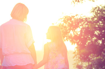 Little daughter looking at her mother, holding her hand when bac