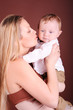 © morrowlight - Young woman kissing baby boy. happy mother holding her child. Motherhood