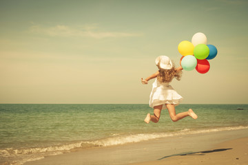 Wall Mural - Teen girl with balloons jumping on the beach