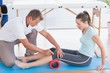 Trainer working with woman on exercise mat 