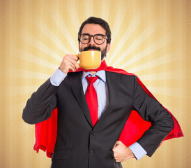 Wall Mural - Businessman dressed like superhero drinking coffee