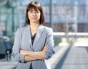 Wall Mural - Serious business woman in gray suit standing in the city