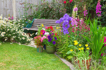 Cottage garden with bench and containers full of flowers