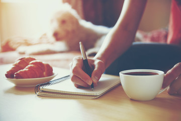 Wall Mural - female hands with pen writing on notebook with morning coffee an