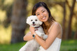 Cute girl with white dog smiling and hugging at the park outdoors