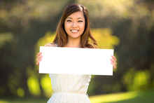 A Beautiful Young Adult Woman Holding A Blank White Sign Card Outdoors Smiling Confident