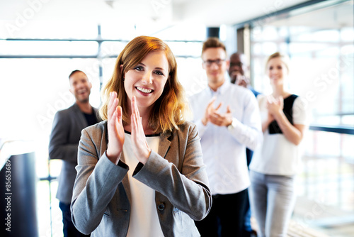 Fotografía White female executive standing in front of colleagues clapping
