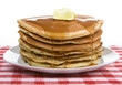 Big Stack of Pancakes – A huge stack of pancakes, covered with maple syrup and butter. On a white plate and red checked tablecloth in background.