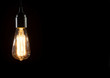 A classic Edison light bulb on black background with space for text