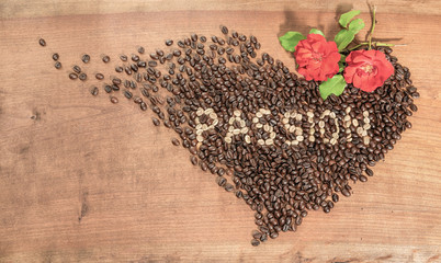  Ziarna kawy z czerwonymi różami ułożone w kształcie serca na szorstkiej powierzchni drewnianej, napisane z surowych ziaren kawy.