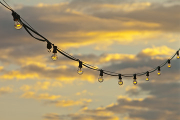 Lamp string hanging against a goldish sky background