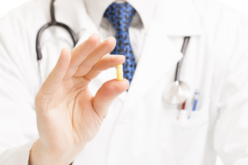 Wall Mural - Doctor holding pill with two fingers - studio shot