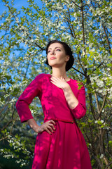 Wall Mural - young beautiful woman in pink dress posing in blooming garden