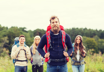 Canvas Print - group of smiling friends with backpacks hiking