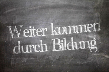 Wall Mural - Next come through education (in German) written on a chalkboard