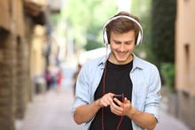 Guy Walking And Using A Smart Phone With Headphones