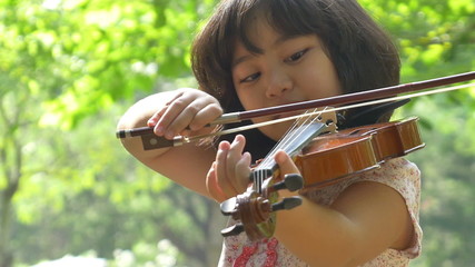 Wall Mural - little asian girl playing violin in the park