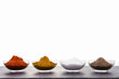 Pfeffer, Salz, Curry, Paprika in Schalen und in Reihe auf einer Steinplatte arrangiert