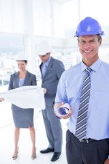 Wall Mural - Businessmen and a woman with hard hats and holding blueprint