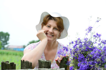 Woman with   wildflowers near  wooden fence in the village