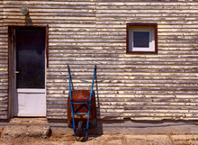 Rusty Old Wheelbarrow Leaning Against Wall