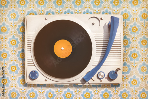 Fotografía Vintage record player on top of flower wallpaper