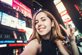 Fototapeta  - Young woman tourist takes selfie photo on Times Square, New York, USA