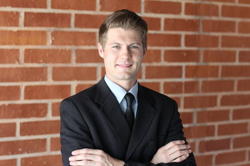 Portrait of an attractive young businessman in urban background wearing blue suit a necktie. Blonde hair