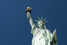 Front View Of The Statue Of Liberty Holding Her Torch Against Clear Bright Blue Sky