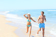 © goodluz - Couple having fun running on the beach