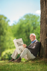 Sticker - Senior man reading a newspaper in park