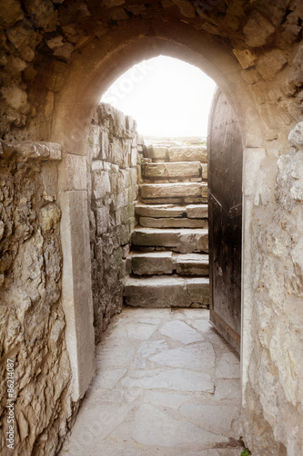 Naklejka na drzwi Stone wall with open door and rays of light behind