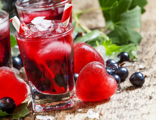 Red cold cocktail with berries currants and red heart-shaped ice