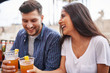 happy hispanic couple drinking beer in outdoor pub
