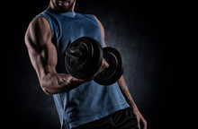Young Man With Dumbbell Flexing Muscles Over Gray Background
