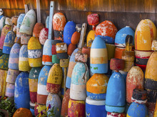 Colorful Bouys Hang On The Side Of A Fishing Shack In Coastal Maine.