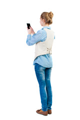 Wall Mural - back view of standing young beautiful  woman  in vest and using