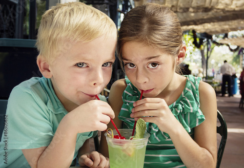 Valokuva Cute kids sharing a mint julep drink at a cafe