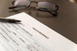 Health insurance application form on a wooden table with glasses
