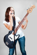 Girl singing with microphone and bass guitar isolated on gray background