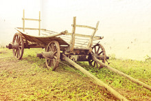 Vintage Old Rough Wooden Cart In Front Of Old Clay Wall.