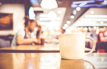 Wall Mural - Vintage filter, White coffee cup on wood table with blurred cafe